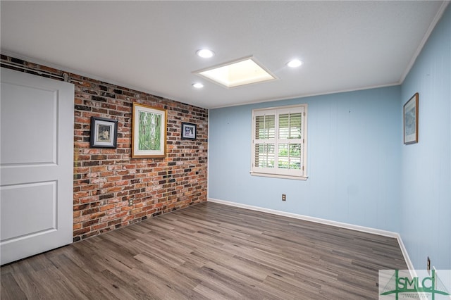 unfurnished room with wood-type flooring and brick wall