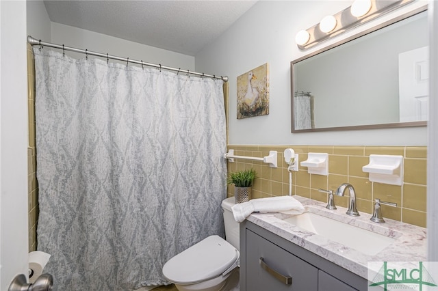 bathroom with tile walls, vanity, a textured ceiling, curtained shower, and toilet