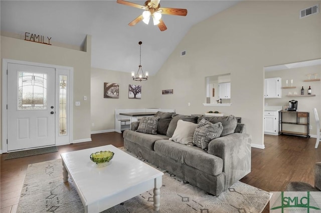 living room with ceiling fan with notable chandelier, dark hardwood / wood-style flooring, and high vaulted ceiling