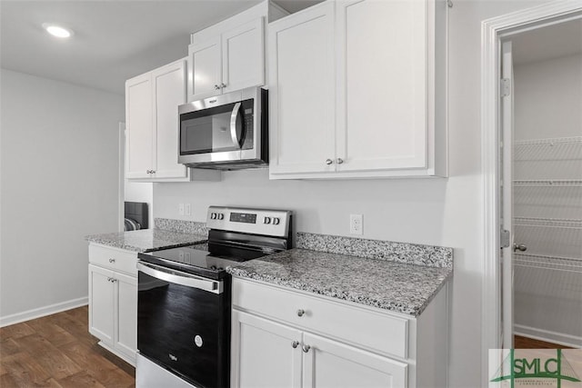 kitchen with light stone countertops, appliances with stainless steel finishes, dark wood-type flooring, and white cabinets