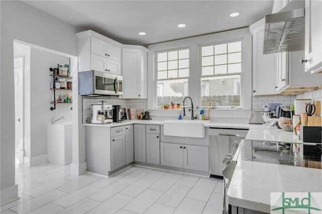 kitchen featuring sink, appliances with stainless steel finishes, light stone countertops, decorative backsplash, and white cabinets