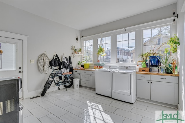 laundry area with separate washer and dryer and cabinets