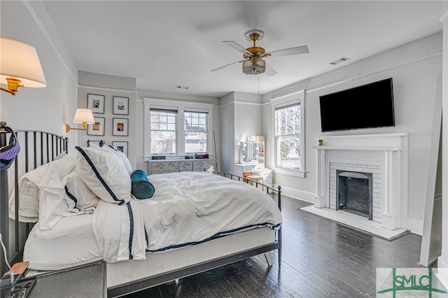 bedroom with ceiling fan, a fireplace, and dark hardwood / wood-style flooring