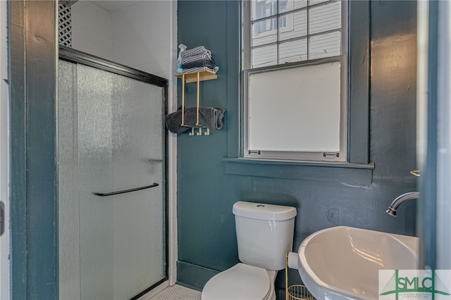 bathroom with toilet, a shower with shower door, and sink