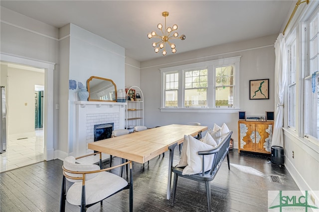 dining area with a brick fireplace, dark hardwood / wood-style floors, and a chandelier