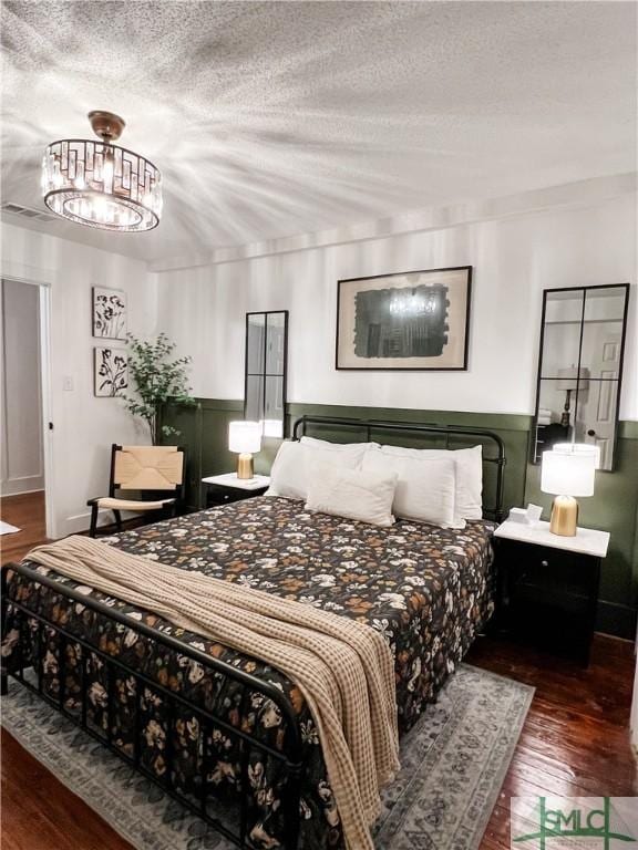 bedroom with dark wood-type flooring, a chandelier, and a textured ceiling