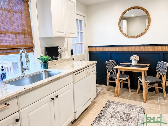 kitchen with light tile patterned flooring, sink, white cabinetry, light stone counters, and dishwasher