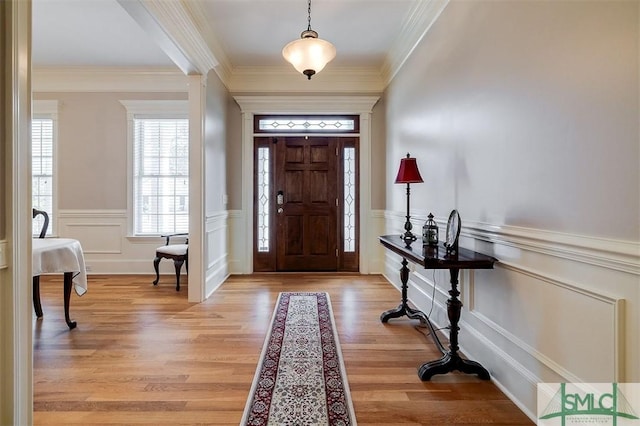 entrance foyer featuring ornamental molding and light hardwood / wood-style floors