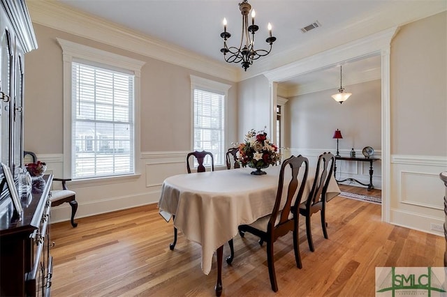 dining space featuring ornamental molding, light hardwood / wood-style flooring, and a notable chandelier