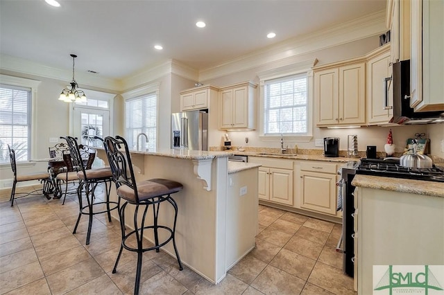 kitchen featuring appliances with stainless steel finishes, decorative light fixtures, sink, a center island, and light stone counters