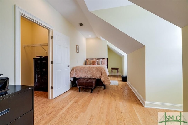 bedroom with a spacious closet and light wood-type flooring