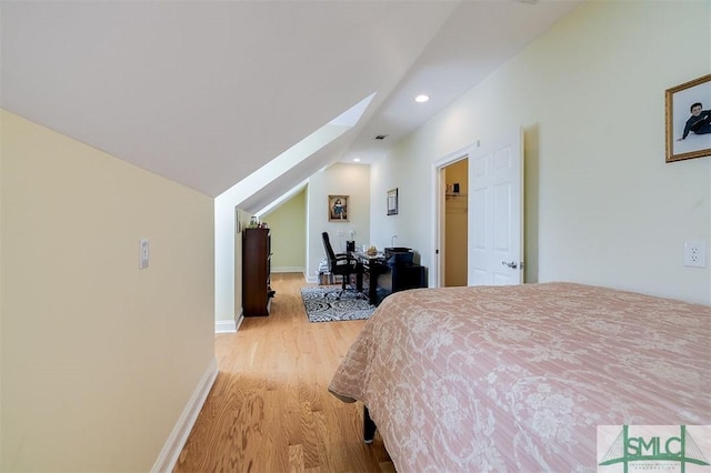 bedroom with lofted ceiling with skylight and light hardwood / wood-style flooring