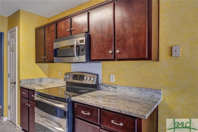 kitchen with light stone counters, light tile patterned floors, and stainless steel appliances