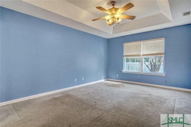 spare room featuring carpet floors, a raised ceiling, and ceiling fan