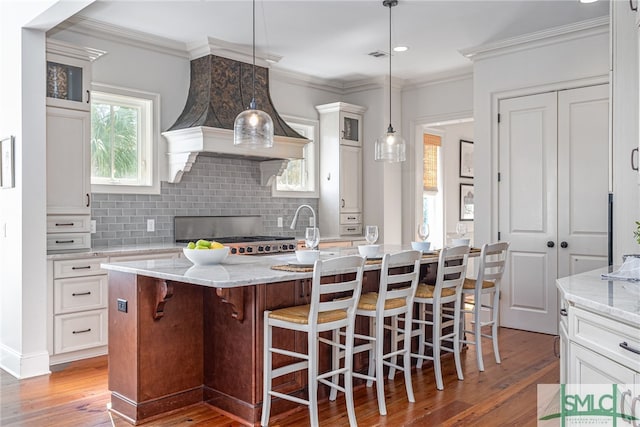 kitchen featuring light stone countertops, a kitchen island with sink, and a kitchen breakfast bar