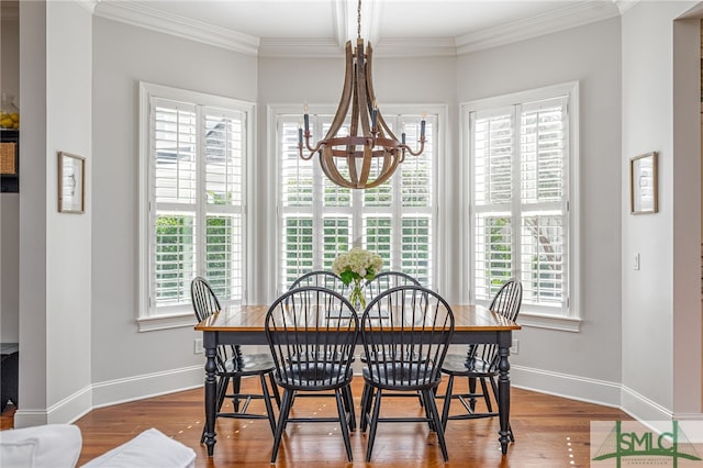 dining space with hardwood / wood-style flooring, crown molding, a wealth of natural light, and an inviting chandelier