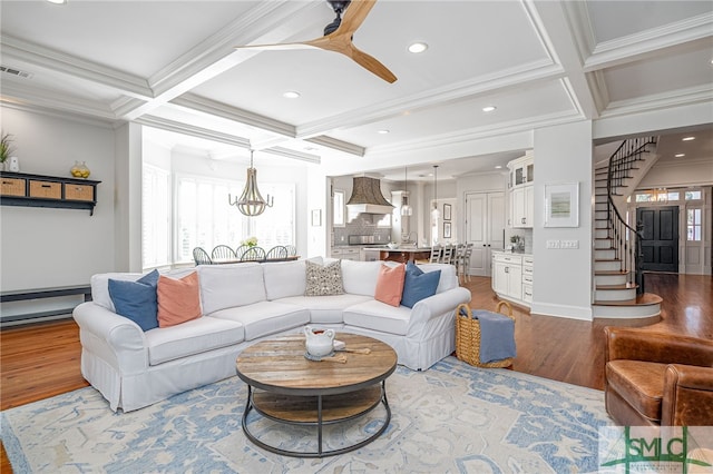 living room featuring coffered ceiling, a wealth of natural light, light hardwood / wood-style flooring, and crown molding