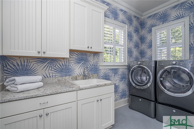 clothes washing area with crown molding, washing machine and clothes dryer, sink, and cabinets