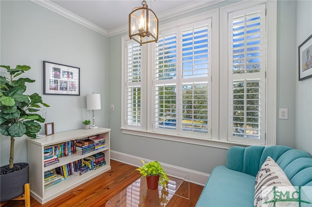 living area with crown molding, wood-type flooring, a chandelier, and a healthy amount of sunlight