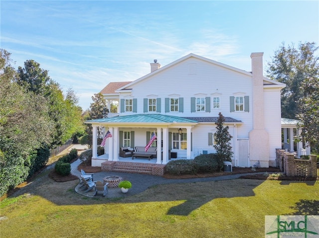 rear view of property featuring a yard and a fire pit