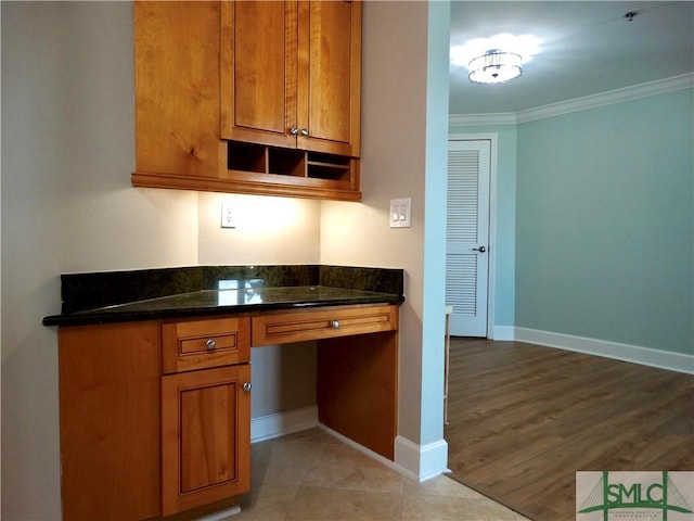 kitchen with ornamental molding, built in desk, and dark stone countertops