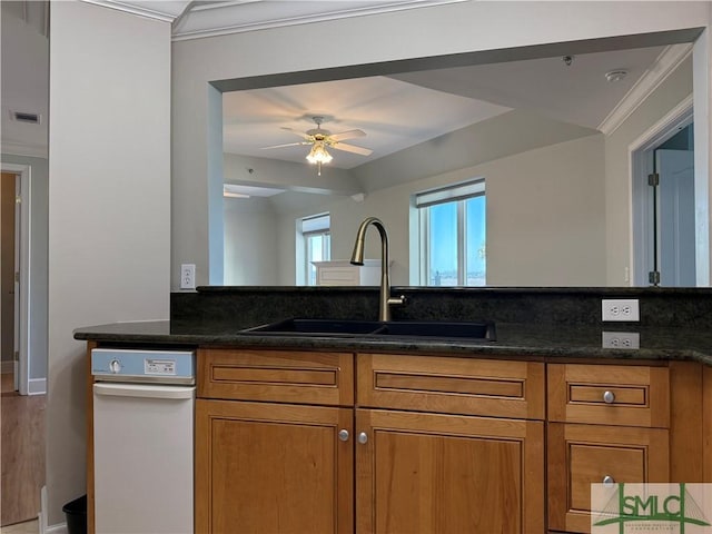 kitchen featuring dark stone countertops, sink, crown molding, and ceiling fan