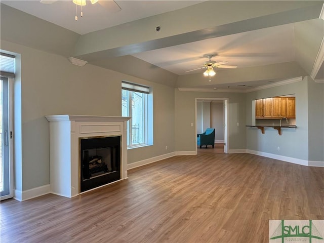 unfurnished living room featuring ceiling fan, lofted ceiling, light hardwood / wood-style flooring, and ornamental molding