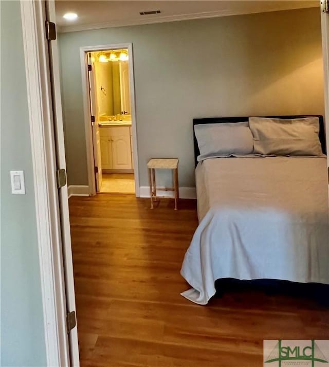 bedroom with crown molding, sink, hardwood / wood-style floors, and ensuite bath