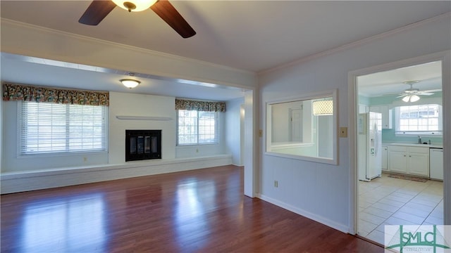 unfurnished living room with crown molding, ceiling fan, and light hardwood / wood-style floors