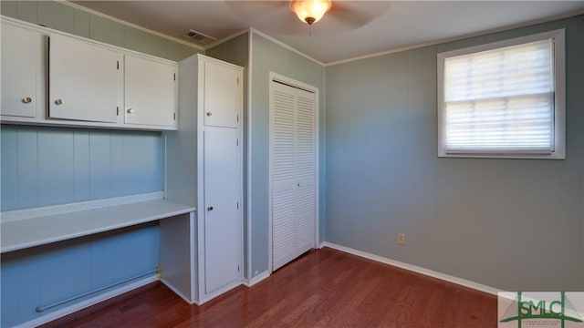 interior space with ornamental molding, dark wood-type flooring, ceiling fan, and a closet