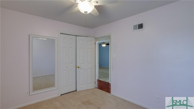 unfurnished bedroom with ceiling fan, a closet, and light carpet