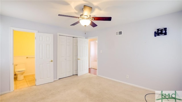 unfurnished bedroom featuring connected bathroom, light carpet, ceiling fan, and a closet