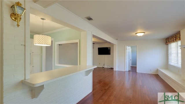 interior space with hanging light fixtures, crown molding, a breakfast bar area, and dark hardwood / wood-style floors