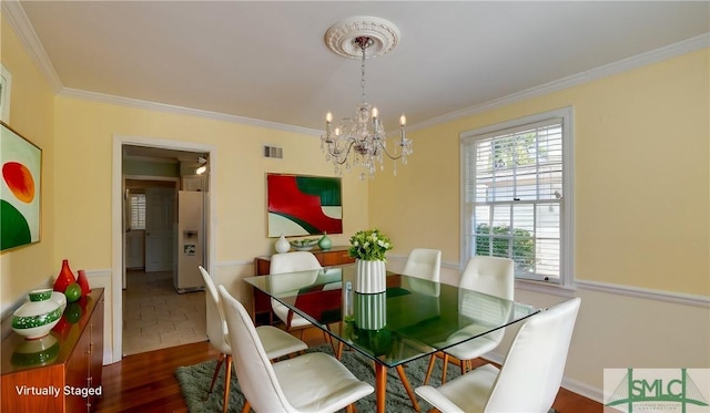 dining space featuring crown molding, dark wood-type flooring, and a notable chandelier