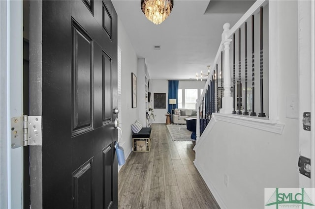 foyer entrance featuring an inviting chandelier and wood-type flooring