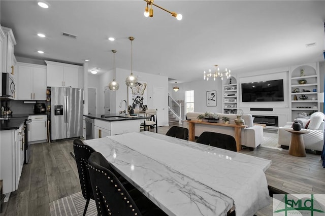 dining area featuring sink, an inviting chandelier, built in features, and dark hardwood / wood-style flooring