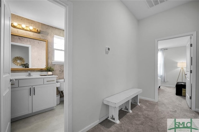 hall with sink and light colored carpet