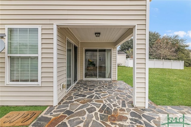 view of exterior entry with a patio area and a lawn