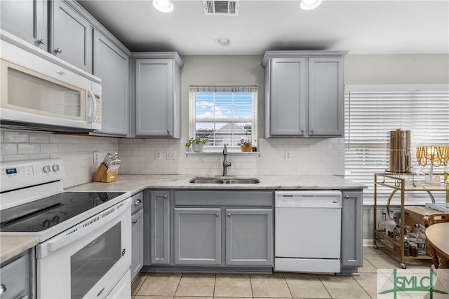 kitchen with gray cabinets, sink, decorative backsplash, light tile patterned floors, and white appliances