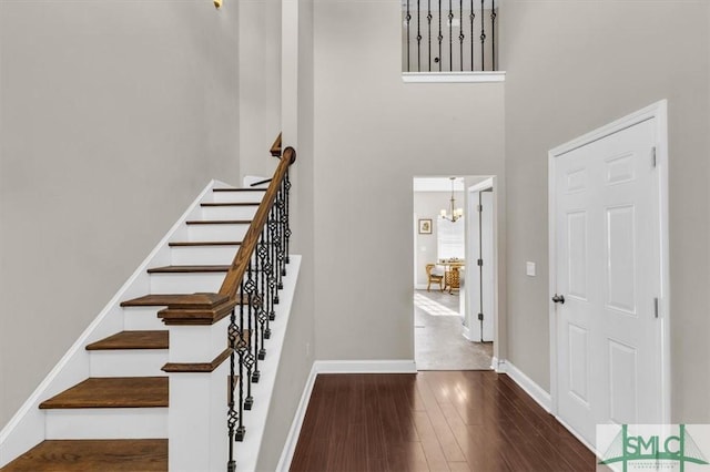 foyer featuring dark wood-type flooring, a towering ceiling, and a chandelier