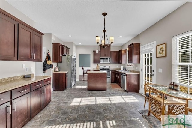 kitchen with sink, dark brown cabinets, appliances with stainless steel finishes, a kitchen island, and pendant lighting