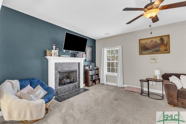 living room with a tiled fireplace, ceiling fan, and carpet flooring