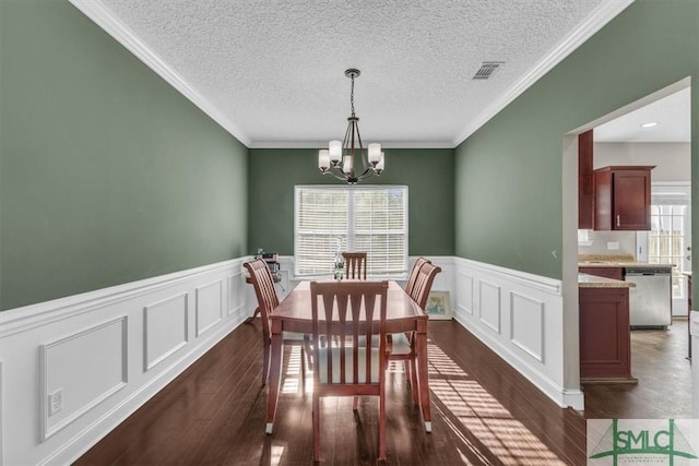 dining room with crown molding, dark wood-type flooring, a notable chandelier, and a textured ceiling