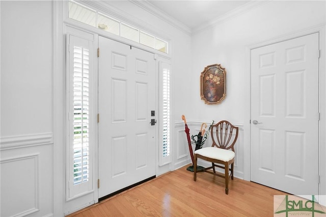 entrance foyer featuring ornamental molding and light hardwood / wood-style floors