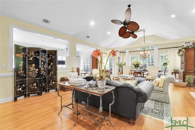 living room with ceiling fan with notable chandelier, wood-type flooring, vaulted ceiling, and ornate columns