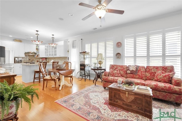 living room with crown molding, light hardwood / wood-style flooring, and ceiling fan