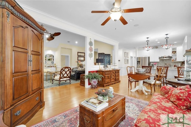 living room with ornamental molding, light hardwood / wood-style floors, and ceiling fan