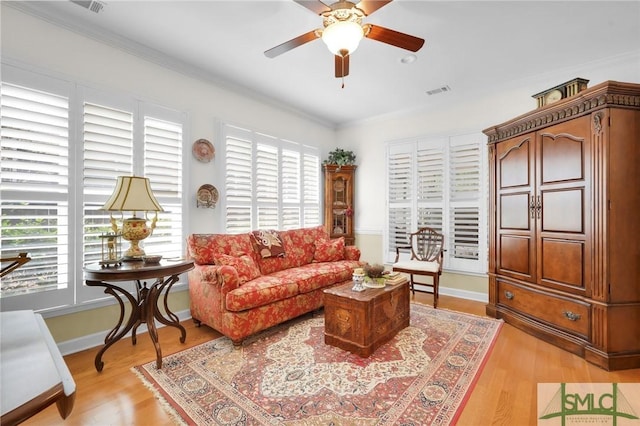 living room with ornamental molding, ceiling fan, and light wood-type flooring