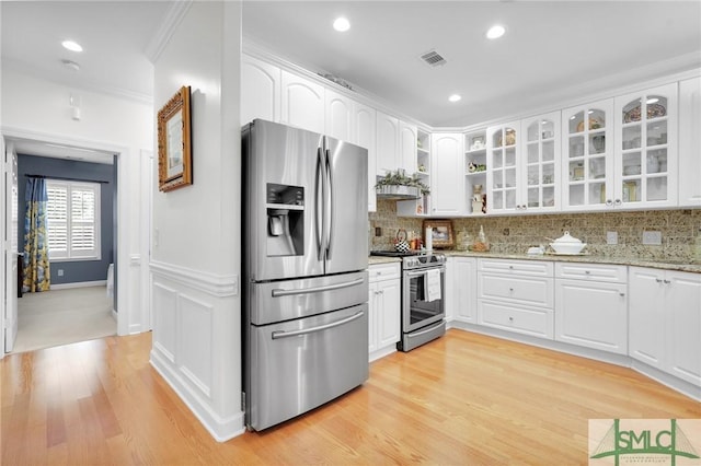 kitchen featuring white cabinetry, tasteful backsplash, light stone counters, light wood-type flooring, and appliances with stainless steel finishes