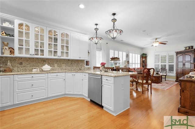 kitchen featuring white cabinetry, hanging light fixtures, light hardwood / wood-style floors, stainless steel dishwasher, and kitchen peninsula